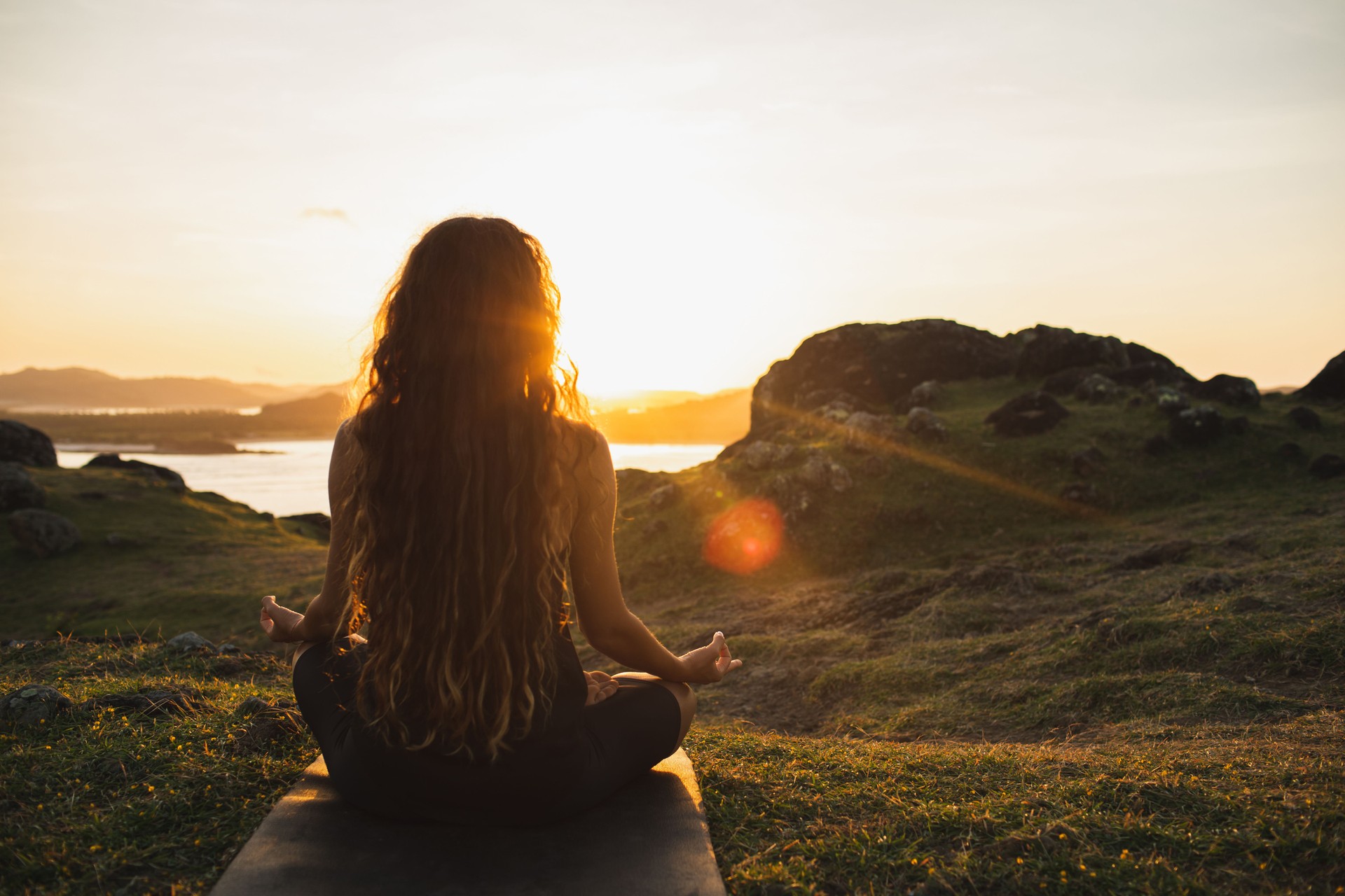 Mujer meditando yoga sola en las montañas del amanecer. Vista desde atrás. Concepto de relajación espiritual de estilo de vida de viaje. Armonía con la naturaleza.